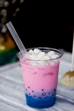 bubble tea in pink and blue color in a plastic Cup with a straw. The top is sprinkled with marshmallows.Soft, beautiful colorsの写真素材
