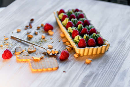 Pistachio tart. Pistachio tart on white Belgian chocolate BARRY with a layer of raspberry confit, crispy shortbread base, fading cream and juicy raspberries.A classic combination in miniature format.の写真素材