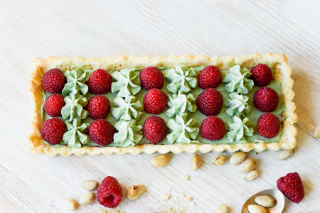 Pistachio tart. Pistachio tart on white Belgian chocolate BARRY with a layer of raspberry confit, crispy shortbread base, fading cream and juicy raspberries.A classic combination in miniature format.の写真素材