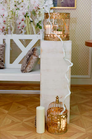 Golden cage with candles on a white wooden pedestal.Wedding photo zoneの写真素材