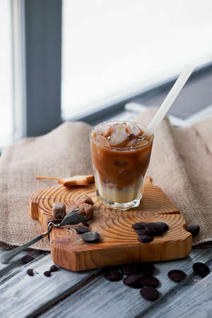 The Hong Kong iced coffee in a glass,with a straw. interesting wooden backgroundの写真素材