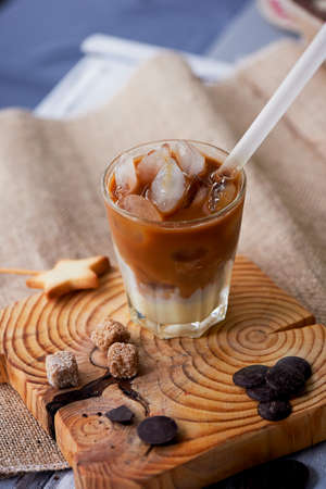 The Hong Kong iced coffee in a glass,with a straw. interesting wooden backgroundの写真素材