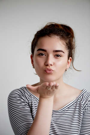 Cute lovely young woman standing and sending kiss over white background. Flying Kiss,Woman in Love .の写真素材