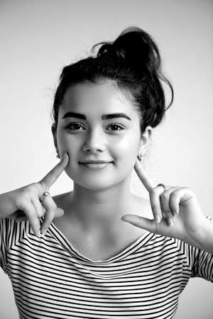 Surprised woman with hands up amazed or shocked by unexpected news holding close palms up and showing happy expression. Young adult woman on greybackgroundの写真素材