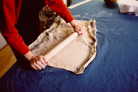master shapes pottery on a blue canvas. Creative process. Gives shape to your product.Spread the clay with a rolling pinの写真素材
