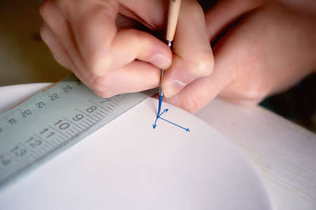 The artist paints an anchor on a white plate made of clay. Painted, handmadeの写真素材