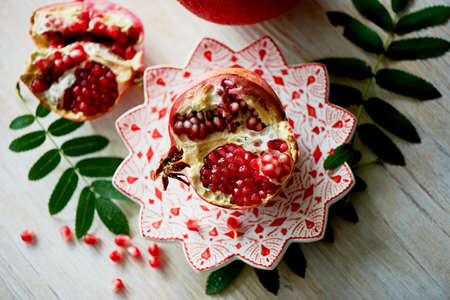 Fresh juicy pomegranate on a light background. On the wooden end of it. Next brush the ash. Healthy eating. Vegetarianismの写真素材