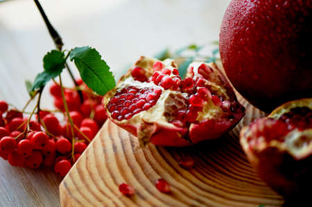 Fresh juicy pomegranate on a light background. On the wooden end of it. Next brush the ash. Healthy eating. Vegetarianismの写真素材