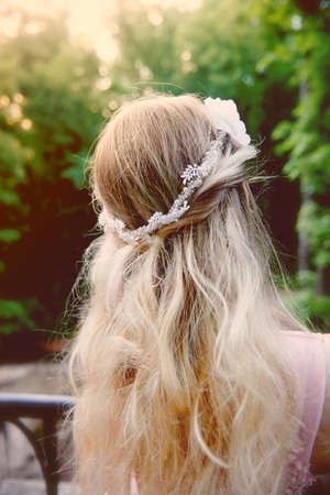 Portrait of a beautiful bride blond girl in pink lace dress ,hair decoration, handmade. Tenderness. Rear view, focus on the hairの写真素材