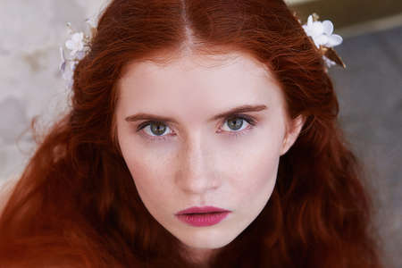 Portrait of a beautiful redheaded girl with long curly hair. Bride. With handmade jewelry on the hair. Hair to the waist. Very long red hair. Big facialの写真素材