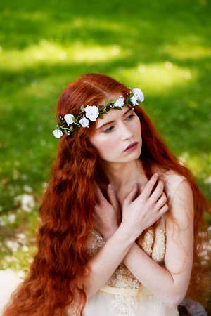 Portrait of a beautiful redheaded girl with long curly hair. Bride. With handmade jewelry on the hair. Hair to the waist. Very long red hair. The average planの写真素材