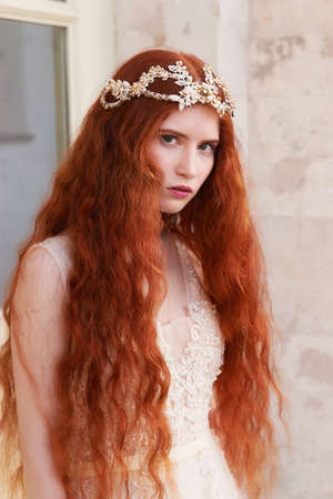 Portrait of a beautiful redheaded girl with long curly hair. Bride. With handmade jewelry on the hair. Hair to the waist. Very long red hair. The average planの写真素材