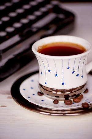 Old metal typewriter, covered in dust and rust. Cup of coffee on the table. The atmosphere of comfort and creativity. Retroの写真素材