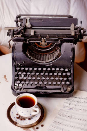 Old metal typewriter, covered in dust and rust. Cup of coffee on the table. The atmosphere of comfort and creativity. Retroの写真素材