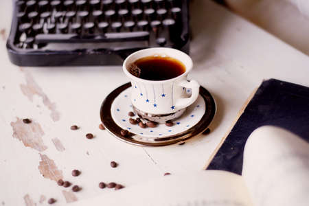 Old metal typewriter, covered in dust and rust. Cup of coffee on the table. The atmosphere of comfort and creativity. Retroの写真素材