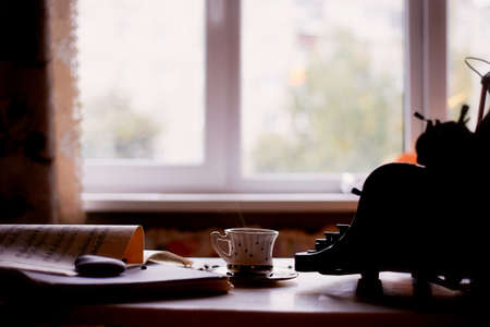 Old metal typewriter, covered in dust and rust. Cup of coffee on the table. The atmosphere of comfort and creativity. Retroの写真素材