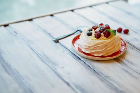 Dessert Anna Pavlova with raspberries and blueberries on white wooden surfaceの写真素材
