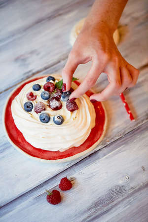 Dessert Anna Pavlova with raspberries and blueberries on white wooden surfaceの写真素材