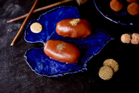 Chocolate potato cake with gold powder on the deep blue plate. A work of culinary artの写真素材