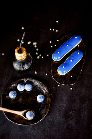 Blue eclairs and candy in blue colors. On a dark background. Pastry artsの写真素材