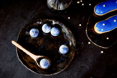 Blue eclairs and candy in blue colors. On a dark background. Pastry arts