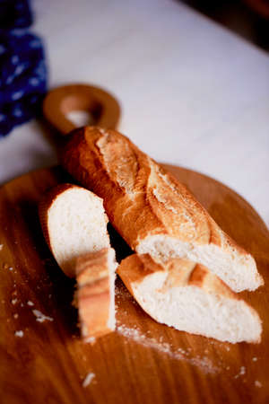 Sliced fresh baguette lying on a wooden Board. Taking pictures of the food.