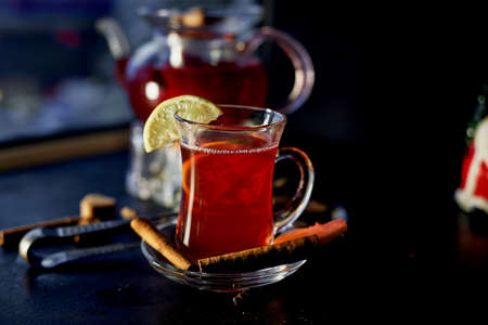 The atmosphere of new year atmosphere. Kettle on stand with warming candles. In a kettle of mulled wine or hibiscus tea with lemon. Cinnamon sticks and orange.の写真素材