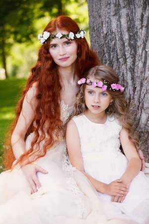 The red-haired girl with the baby, daughter or sister. Delicate and long-haired.の写真素材