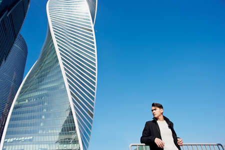 The young man in classic clothing standing on a background of skyscrapers. The concept of success and developmentの写真素材