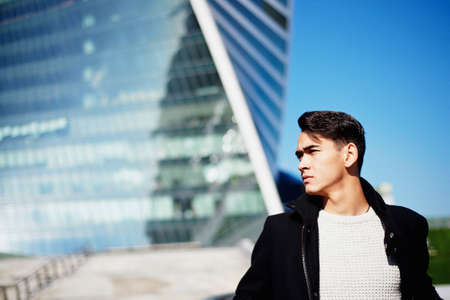 The young man in classic clothing standing on a background of skyscrapers. The concept of success and developmentの写真素材