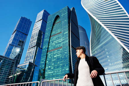 The young man in classic clothing standing on a background of skyscrapers. The concept of success and developmentの写真素材