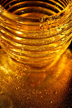 Golden texture with water drops. Thirst and its quenching. Drops of honey on the glassの写真素材
