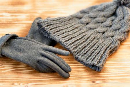 grey hat and gloves knit on a wooden surface. The concept is to keep warm in autumn or winter dayの写真素材