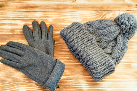 grey hat and gloves knit on a wooden surface. The concept is to keep warm in autumn or winter dayの写真素材