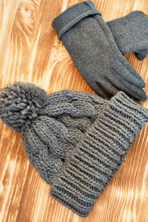 grey hat and gloves knit on a wooden surface. The concept is to keep warm in autumn or winter dayの写真素材