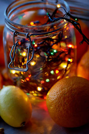 New years table. Garland, glowing in a glass jar. Among the citrusの写真素材