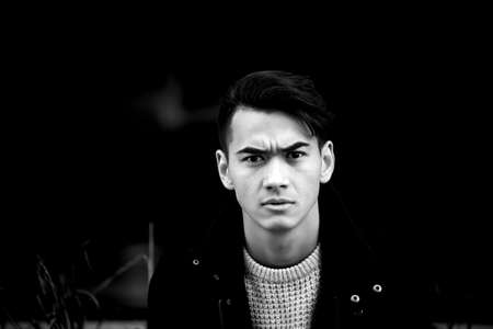 A young man with dark hair and eyes frowns.Reverie. Frowns. Model posing, emotionsの写真素材