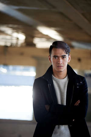 A young man, thin. With dark hair and brown eyes. Standing under a bridge by the river, hands...