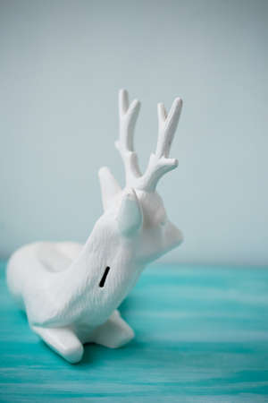 Decorative plaster deer piggy Bank white color. On a turquoise surfaceの写真素材