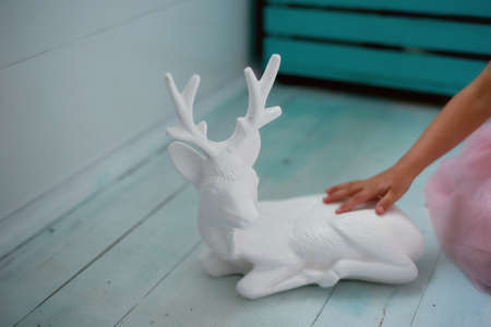 A lovely little girl 4 years old in a pink dress plays with pink deer. The atmosphere of childhoodの写真素材