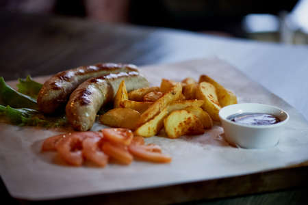 Hearty, fatty dish to the table. Beer. German national cuisine. Fried sausages with fried potatoes and sauceの写真素材