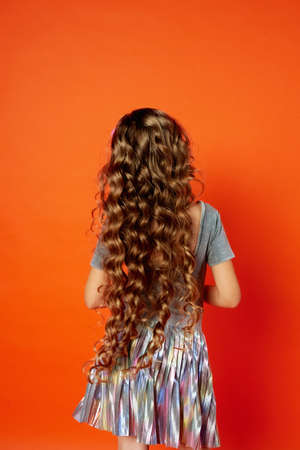 Girl on orange background in the Studio. Very long curly hair like in a fairy tale. Rapunzelの写真素材