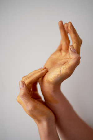 Hands with long fingers in gold paint. Hand careの写真素材