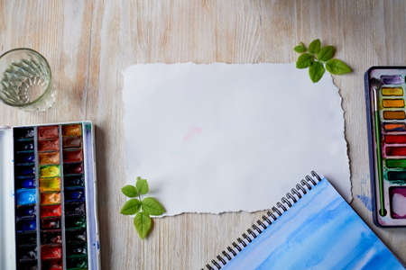 The workplace of the artist. Watercolor paints, a sheet of paper. The view from the topの写真素材