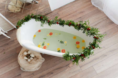 Elegant roll-top bath and decorated with flowers. In the water swim citrus. The atmosphere of...