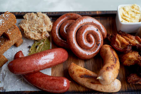 Meat set for a large company on a wooden stand. Grilled sausages, sauerkraut, French fries and saucesの写真素材