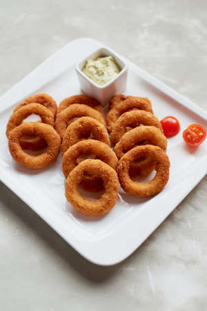 Golden onion rings fried in deep frying. With Sauce on a white plateの写真素材