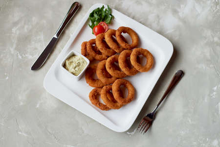 Golden onion rings fried in deep frying. With Sauce on a white plateの写真素材