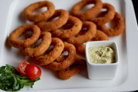 Golden onion rings fried in deep frying. With Sauce on a white plateの写真素材