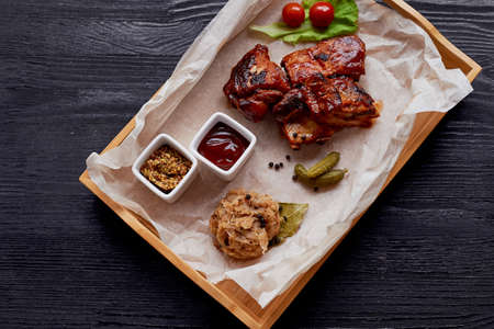 Ribs cooked on the grill with sauerkraut. On parchment paper, decorated with cucumbers and cherry tomatoesの写真素材